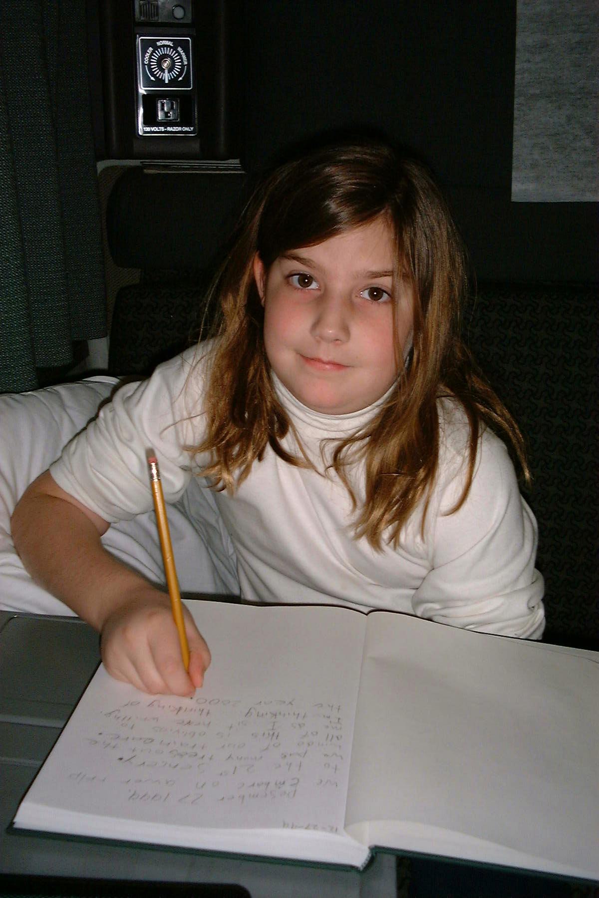 Danielle writing in her journal in the train compartment